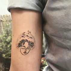 a woman's arm with a sun and moon tattoo on the left inner arm