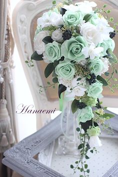 a bouquet of white and green flowers sitting on top of a wooden table next to a chair