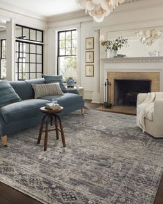 a living room filled with furniture and a fire place under a chandelier hanging from the ceiling