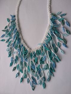 a white necklace with blue beads and green leaves