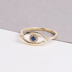 The 14K Evil Eye Ring is a stunning and intricate piece of jewelry that is perfect for any occasion. The ring features a beautiful Evil Eye design, with sparkling CZ diamonds and a vibrant blue sapphire. The Evil Eye is depicted on the ring, adding to its symbolism of protection and good luck. This ring is perfect for everyday wear or as a special occasion piece, and would make a thoughtful gift for any woman in your life. Whether you're looking for a gift for Christmas, Father's Day, Mother's D Exquisite Gold Ring For Promise, 14k Gold Diamond Ring With Diamond Eyes, Gold Sterling Silver Crystal Ring, Gold Crystal Ring In Sterling Silver, Gold Cubic Zirconia Crystal Birthstone Ring, Gold Crystal Birthstone Ring With Cubic Zirconia, Gift Yellow Gold Topaz Ring With Cubic Zirconia, Gold Sapphire Stackable Rings In Fine Jewelry Style, Yellow Gold Topaz Ring With Cubic Zirconia For Gift