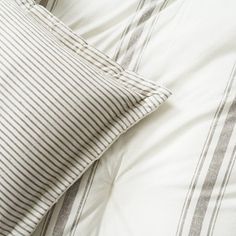 a close up view of a bed with white and grey striped pillows on top of it