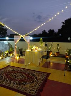 It's a image of a candle light dinner setup on terrace. It has fairy lights, plants, table decoration & carpet. Candle Light Dinner At Home, Candle Light Dinner Ideas, Terrace Party, Light Dinners, Naming Ceremony Decoration, Romantic Candle Light Dinner, Dinner At Home, Naming Ceremony, Dinner Decoration