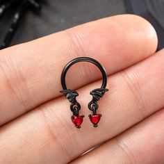 a hand holding a pair of black rings with red crystals on it's sides