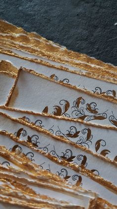 several pieces of white and gold paper with black designs on them are lined up next to each other