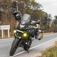 the motorcycle is parked on the side of the road with its lights on and helmet on