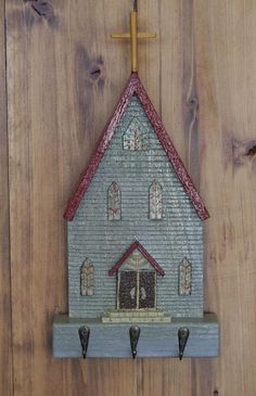 a small church hanging on the side of a wooden wall