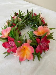 a wreath made out of flowers sitting on top of a white tablecloth with green leaves