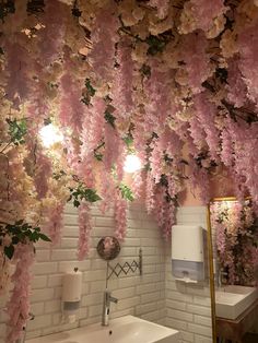 a bathroom with pink flowers hanging from the ceiling and a white sink in front of it