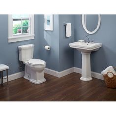 a white toilet sitting next to a sink in a bathroom under a mirror and a window