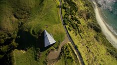 an aerial view of a house on the side of a hill next to the ocean