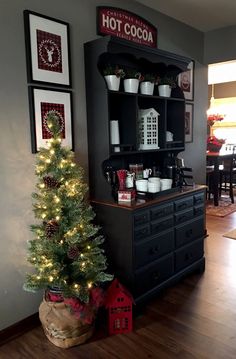 a christmas tree is in front of a hutch with cups on it and other decorations