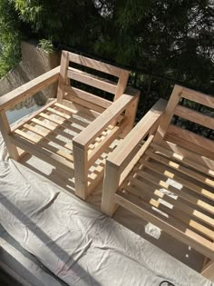 two wooden beds sitting next to each other on top of a tarp covered ground