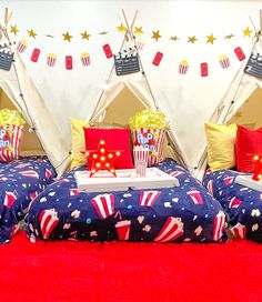 three beds with red, white and blue comforters in front of a teepee tent