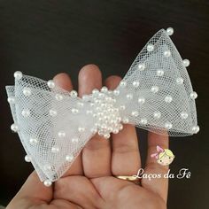 a hand holding a small white bow with pearls on it