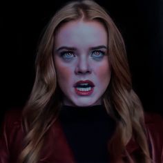 a woman with blue eyes and red lipstick looks at the camera while wearing a leather jacket