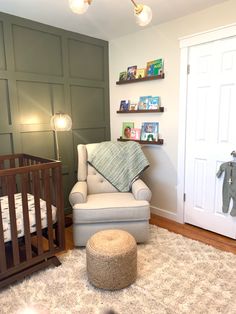 a baby's room with a chair, crib and bookshelf on the wall