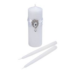 a white candle with a crystal heart on the front and two candles in the back