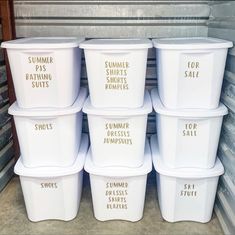 six white plastic containers with gold lettering on them in a storage area next to other bins