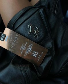 a woman's black leather jacket with a horse emblem on it