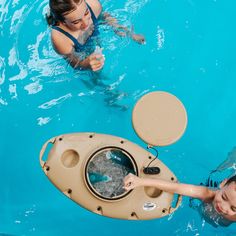 two girls are in the pool playing with an object that looks like a buoy