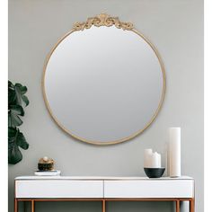 a mirror on the wall above a white table with two candles and a candle holder