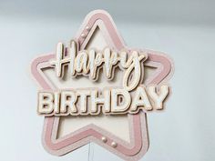 a happy birthday sign hanging from the side of a white and pink star shaped building