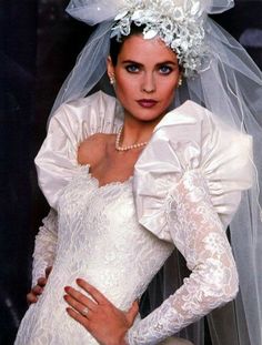 a woman in a wedding dress with a veil on her head is posing for the camera