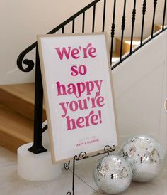 a sign that says we're so happy you're here next to two disco balls