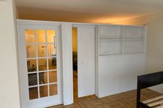 an empty room with white doors and wooden floors