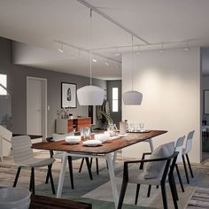 a dining room table with white chairs and plates on the wooden table in front of it