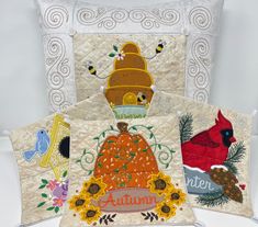 three decorative pillows with embroidered designs on them, one in the shape of a pumpkin