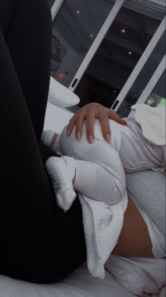 a woman laying on top of a bed covered in white blankets and holding a baby