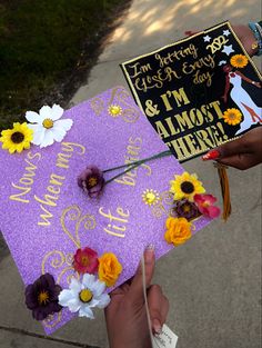 someone is holding up a purple graduation cap with flowers on it that says, i'm almost here