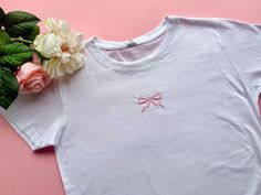 Cute Bow Embroidered Fitted Tee 🎀 Ask for custom colours of bow - please specify below whether you would like a Fitted Women's Tee or Unisex, Baggy Fit T-Shirt! 👇 Please read before ordering 👇 Processing time is 3-7 Days, up to 2 weeks during busier periods. Please make sure before you order that you understand the processing time, your order may be shipped at any point during this period, processing time does not include shipping time! We're only a two person team. Thanks for your understand Pink Short Sleeve T-shirt With Machine Embroidery, Cute Crew Neck Tops With Custom Embroidery, Cute Pink T-shirt With Letter Embroidery, White T-shirt With Machine Embroidery As Gift, White T-shirt With Machine Embroidery For Gift, Embroidered Short Sleeve T-shirt For Gift, Machine Embroidered Short Sleeve T-shirt As Gift, Machine Embroidered Short Sleeve T-shirt For Gift, Cute White T-shirt With Machine Embroidery