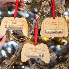 two wooden video game controllers ornament hanging from a christmas tree with red ribbon