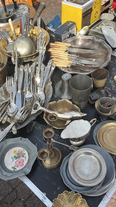 a table topped with lots of silverware on top of a black table covered in plates and bowls