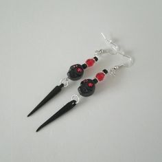 Black Skull Earrings These beautiful handmade earrings have red glass beads, silver plated accent beads, black skulls with red rhinestones and black spikes. The earrings are 3 inches long from the ear hooks. pagan witch gothic witchcraft halloween spooky goth style witchy woman gift Gothic Beaded Earrings, Adjustable Gothic Skull Earrings, Adjustable Black Skull-shaped Earrings, Gothic Skull Earrings, Adjustable Black Skull Earrings, Edgy Handmade Halloween Earrings, Nickel Free Black Skull Earrings, Edgy Handmade Earrings For Halloween, Gothic Skull Jewelry With Ear Wire