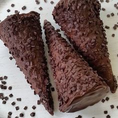 two pieces of chocolate are sitting on a white plate with chocolate chips scattered around it