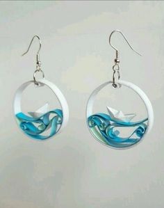 the earrings are decorated with blue swirls and white paper cranes on them, as well as an origami bird