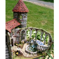 a miniature fairy garden with a fountain and bridge