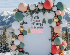 a sign that says oh what fun it is to be one surrounded by balloons in the snow