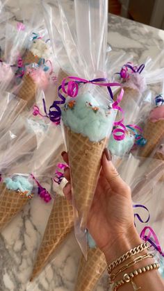 a hand holding an ice cream cone with blue icing and sprinkles