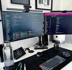 two computer monitors sitting on top of a desk next to a keyboard and monitor screen