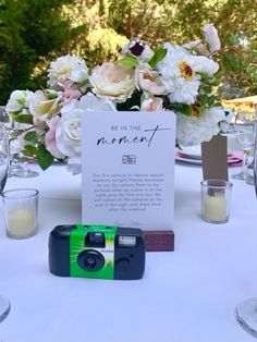 a camera sitting on top of a table next to some glasses and plates with flowers in them