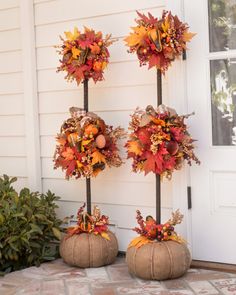 three pumpkins with fall leaves on them sitting in front of a door