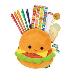 a stuffed hamburger with markers, pens and pencils in it on a white background