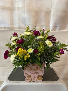 a vase filled with lots of flowers on top of a white tablecloth covered chair