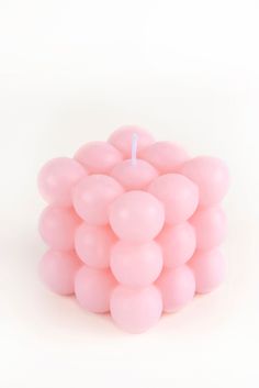 a small pink candle sitting on top of a white table next to a pile of balloons