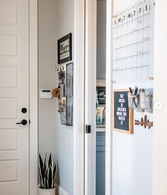 an open door leading to a kitchen with a calendar on the wall and a potted succulent next to it